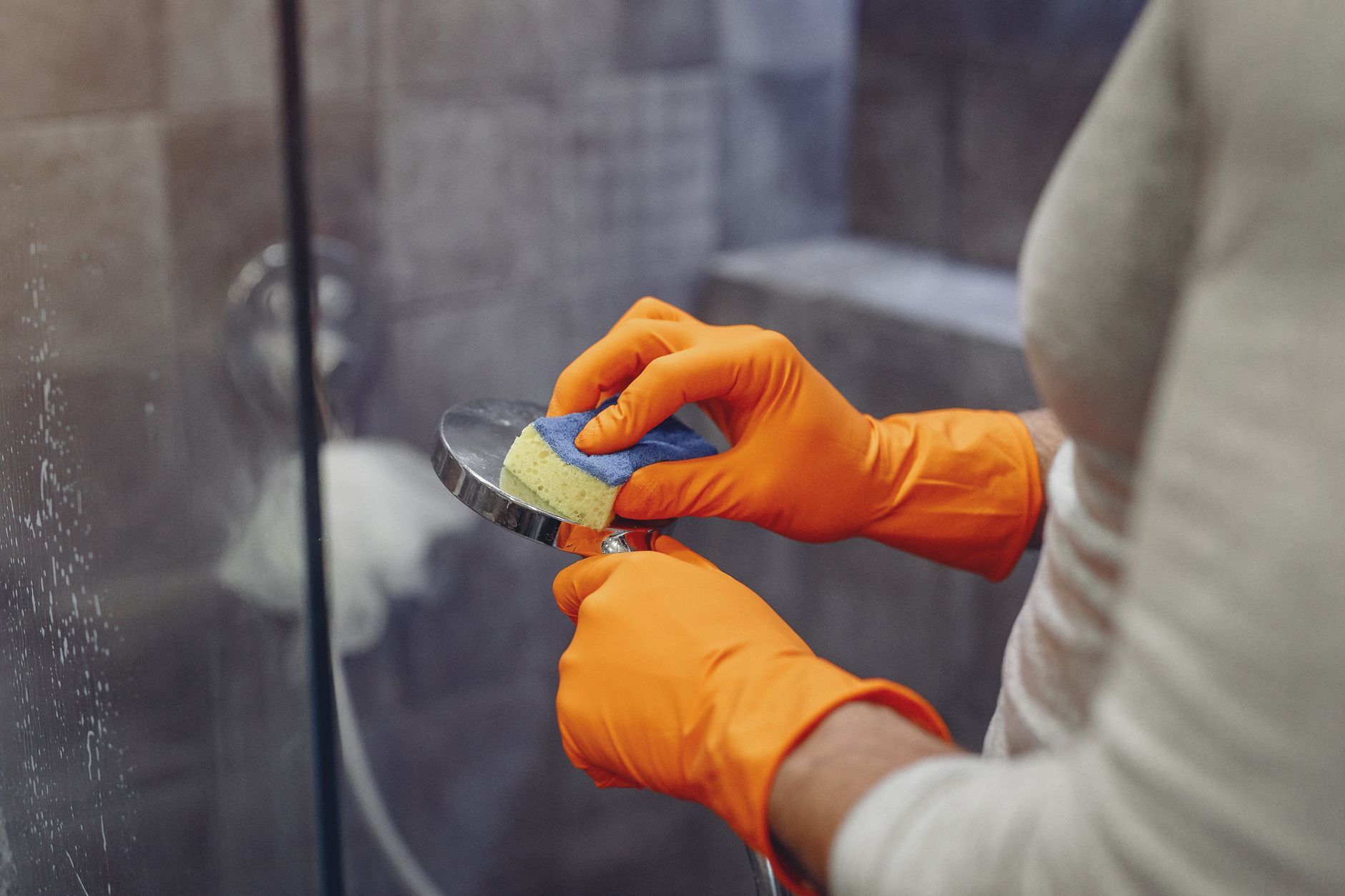 Person cleaning a shower head with a DIY solution